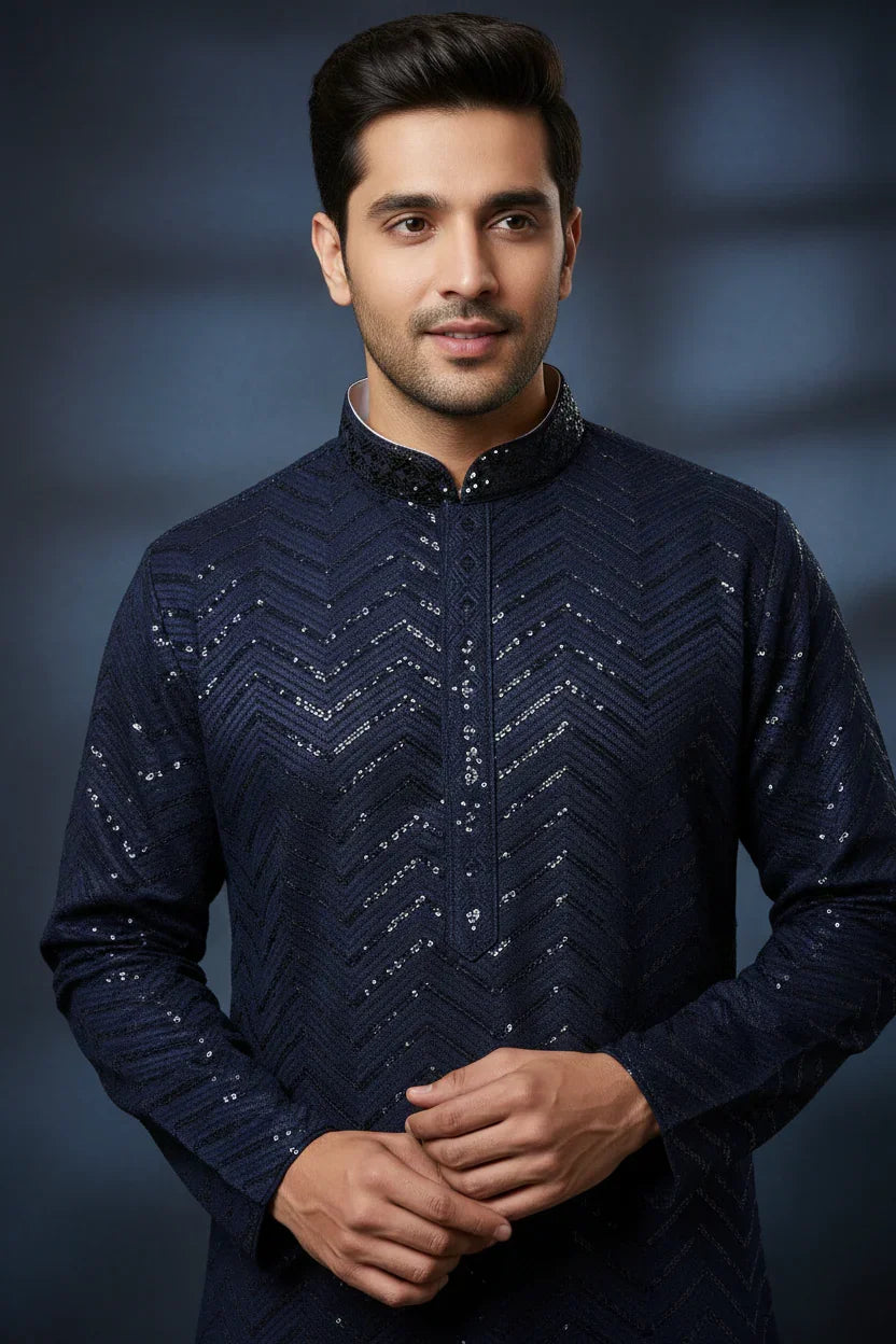 Man wearing navy blue Indian ethnic kurta with sequin chevron pattern, posing against dark background