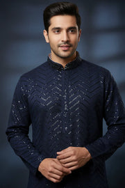 Man wearing navy blue Indian ethnic kurta with sequin chevron pattern, posing against dark background