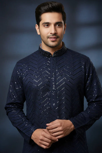 Man wearing navy blue Indian ethnic kurta with sequin chevron pattern, posing against dark background