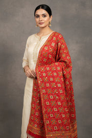 Woman modeling cream ethnic kurta with intricate gold embroidery paired with vibrant red floral bandhani dupatta