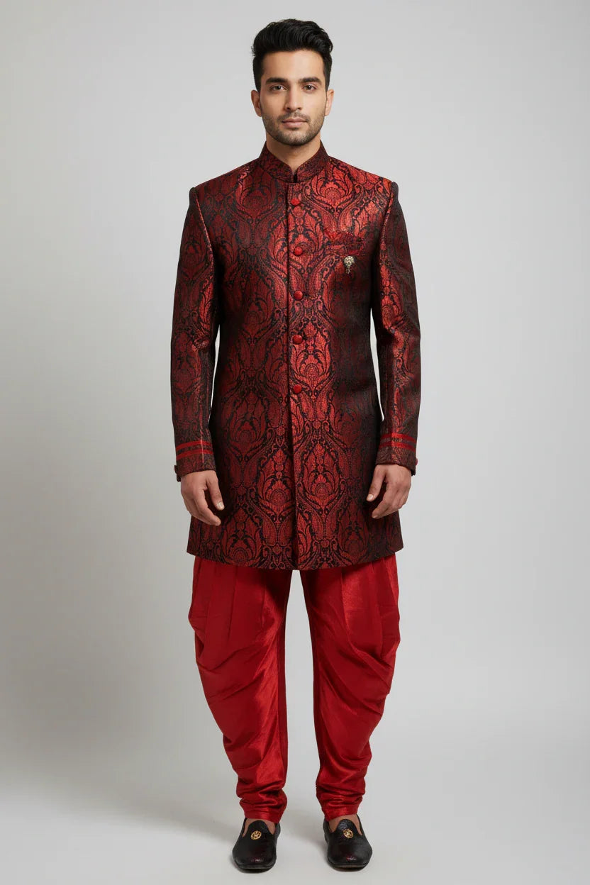 Man wearing red and black brocade sherwani with red silk dhoti pants and black traditional shoes