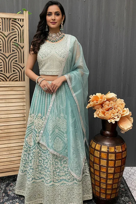 Woman in light blue embroidered lehenga with matching sheer dupatta and traditional jewelry at Anandi Fashions