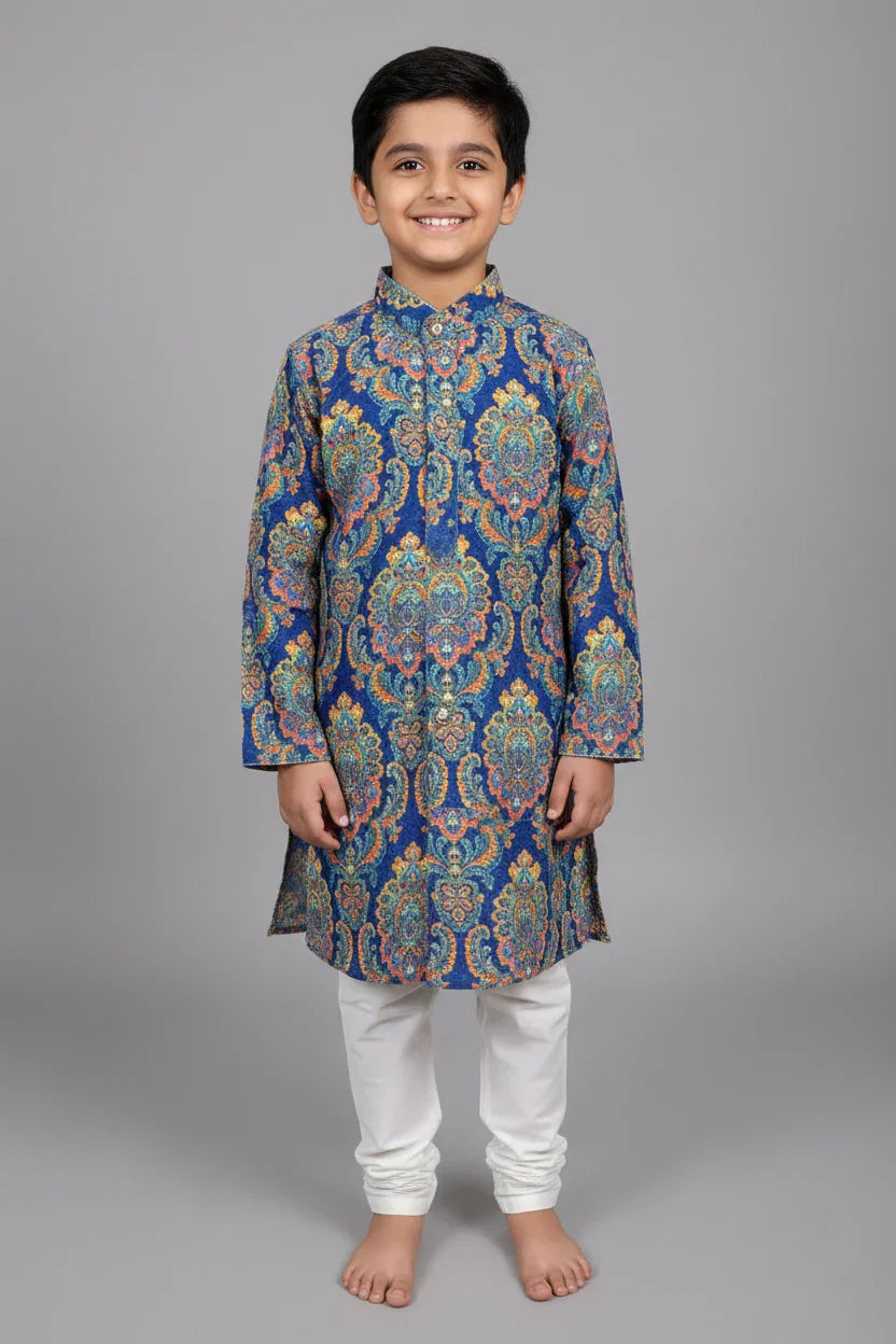 Smiling boy wearing blue floral patterned ethnic kurta with white churidar pants on gray background