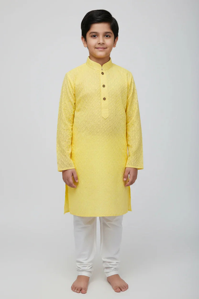 Young boy wearing a yellow textured kurta with white churidar pants, traditional Indian ethnic wear