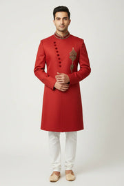 Man wearing red Indian sherwani with embroidery and white churidar pants, traditional ethnic wear