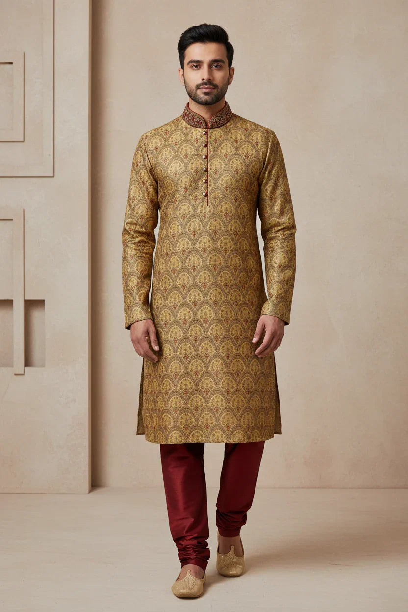 Man wearing gold patterned Indian ethnic kurta with maroon collar and buttons, paired with maroon churidar and beige mojari shoes