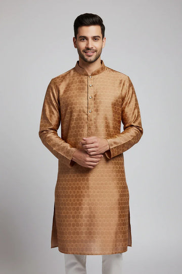 Man wearing gold silk Indian ethnic kurta with patterned design and white pants on gray background