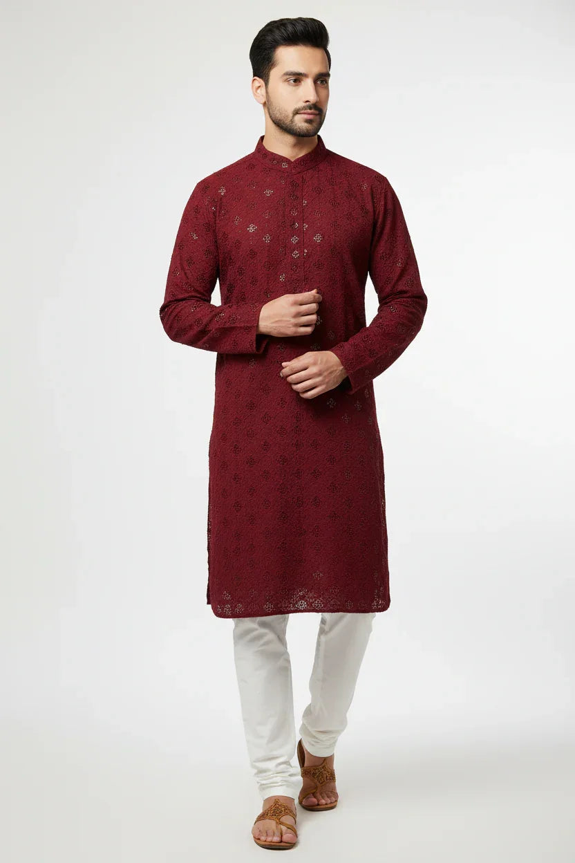 Man wearing a maroon embroidered Indian kurta with white churidar pants and brown sandals