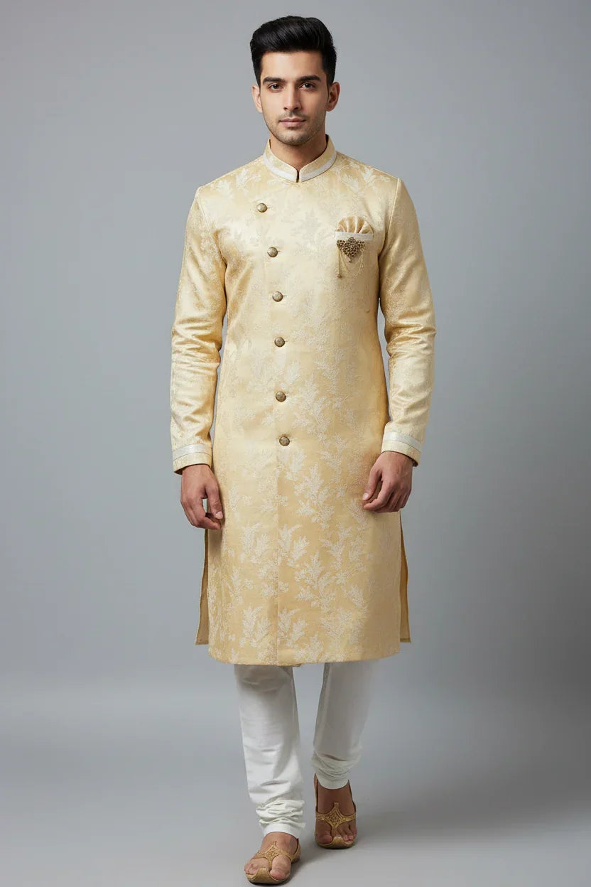 Man wearing elegant golden sherwani with floral patterns and white churidar pants