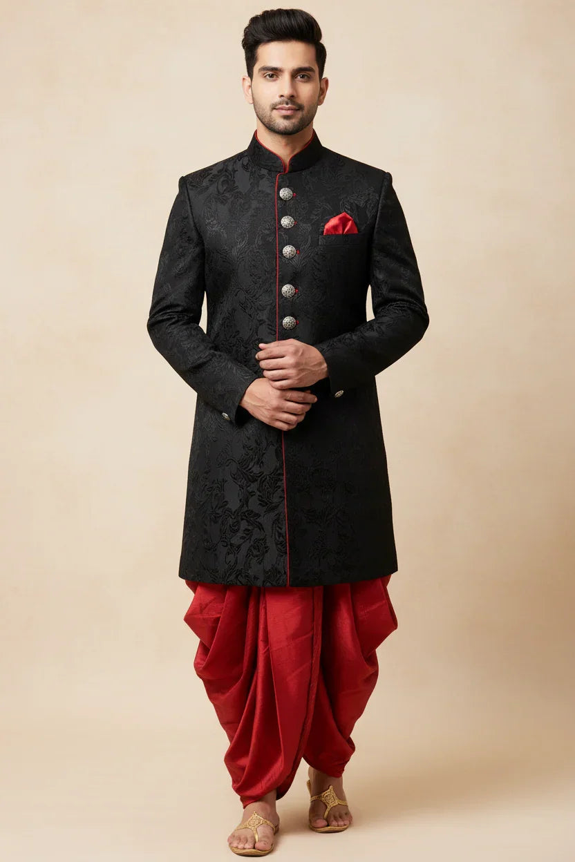 Man in black embroidered sherwani with silver buttons and red pocket square, paired with red dhoti pants and sandals