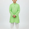 Young boy wearing light green kurta with white churidar and brown traditional shoes on white background
