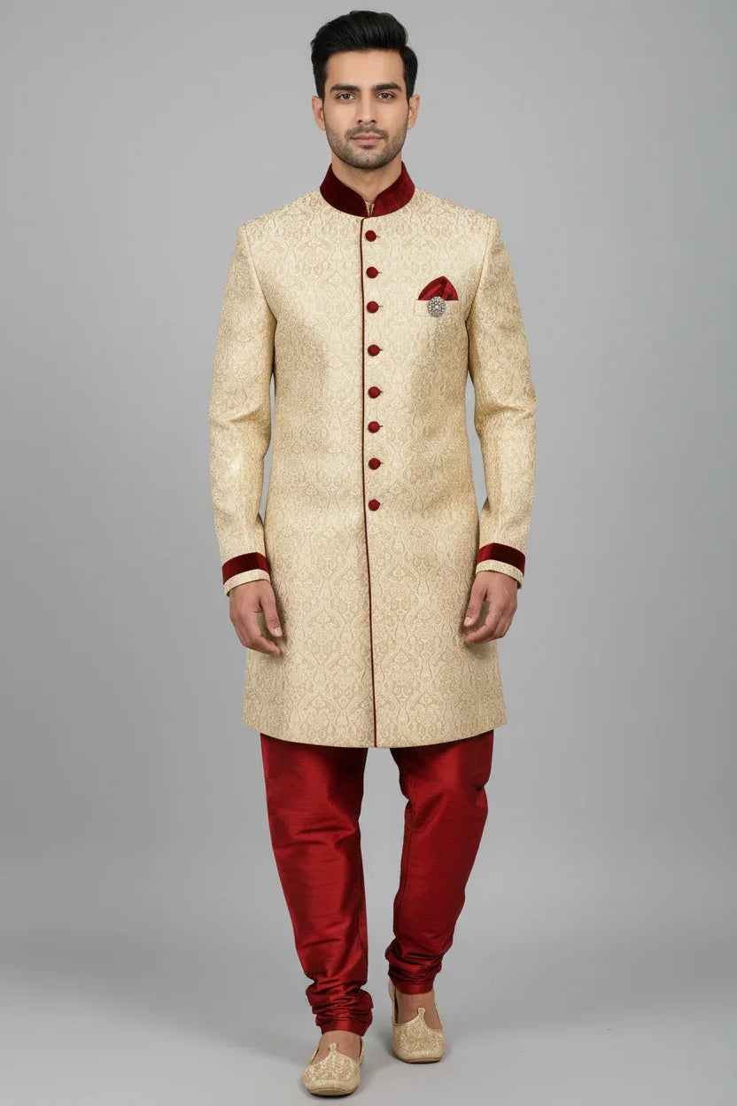 Man wearing cream and maroon embroidered Indian sherwani with maroon churidar pants and beige traditional jutti shoes