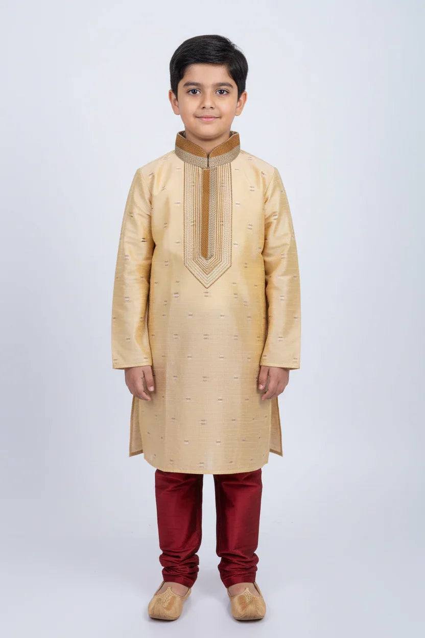 Young boy wearing beige embroidered kurta with maroon churidar and traditional shoes, Indian ethnic wear